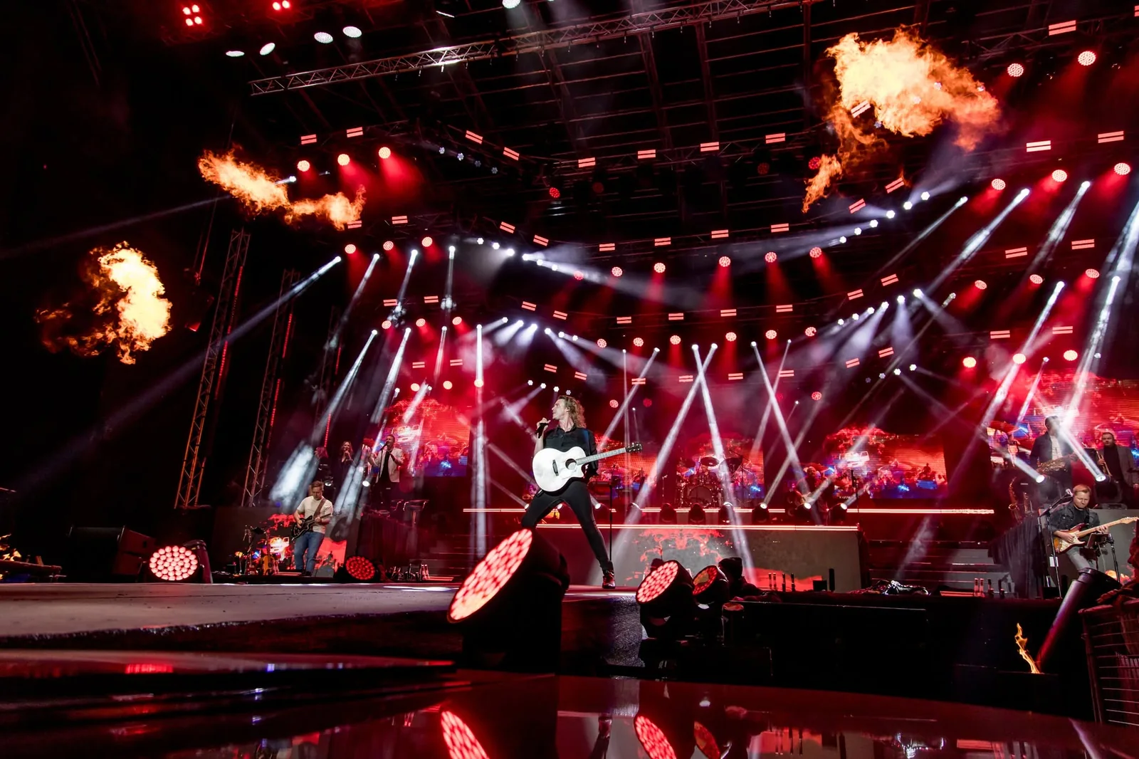 Innibos concert stage with red lighting, white beams, flame effects and a guitarist performing at centre stage