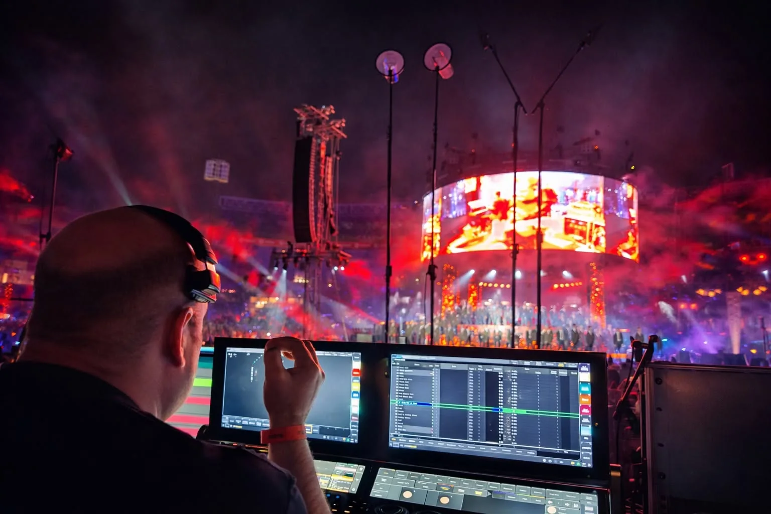 Johan Ferreira programming the Krone concert lighting from a grandMA lighting console with the arena stage visible beyond